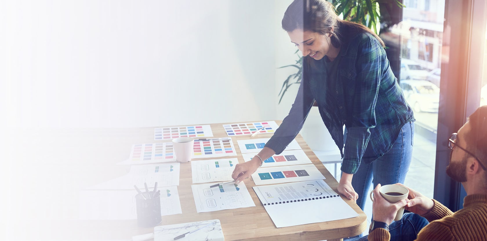 woman leaning over a desk with many papers designing a custom sales training program